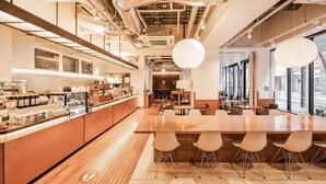 A modern cafe with a long wooden counter, seating area with chairs, and large windows. - OMO3 Tokyo Akasaka by Hoshino Resorts (Tokyo)