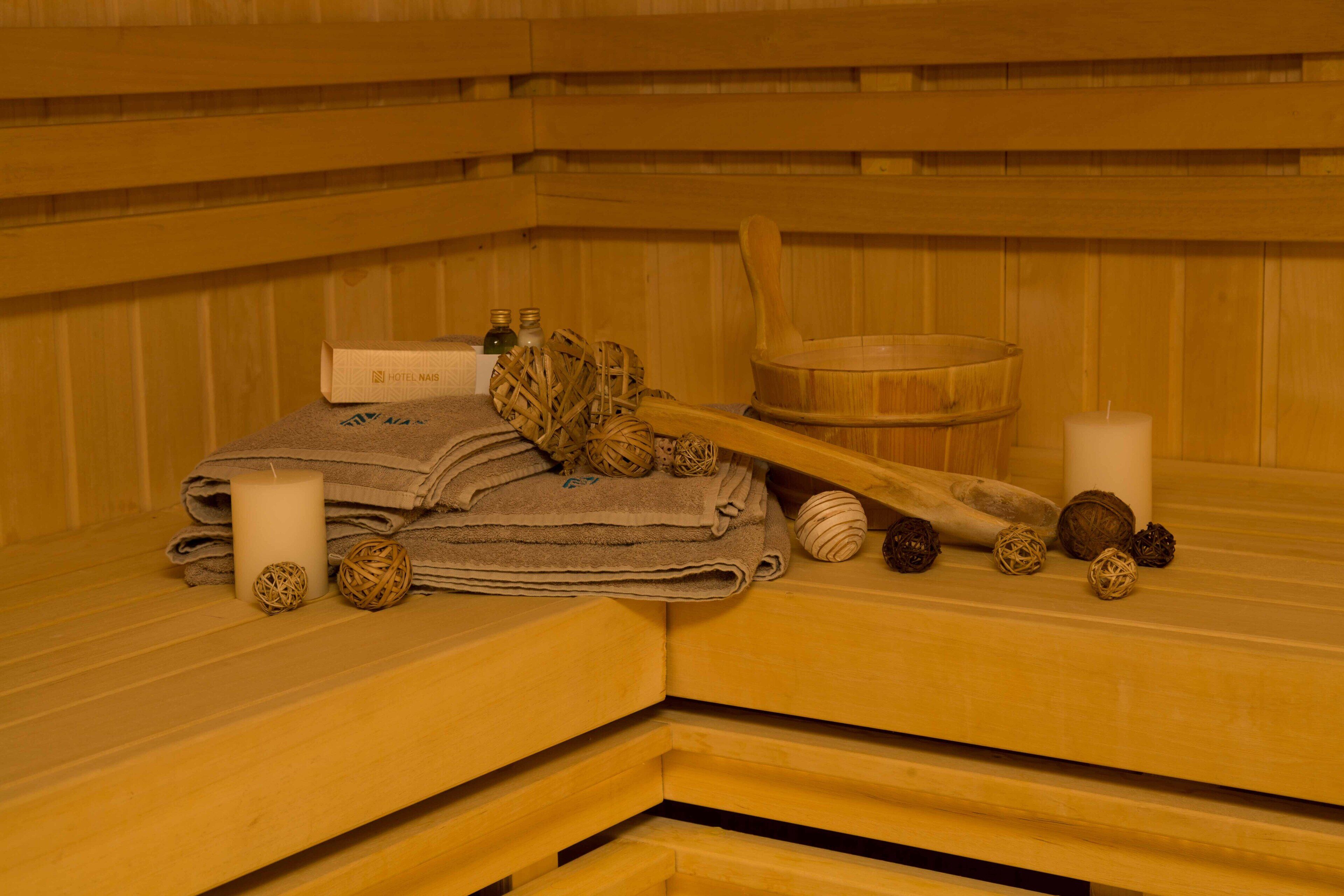 A wooden sauna with towels, candles, and wooden balls on a bench.