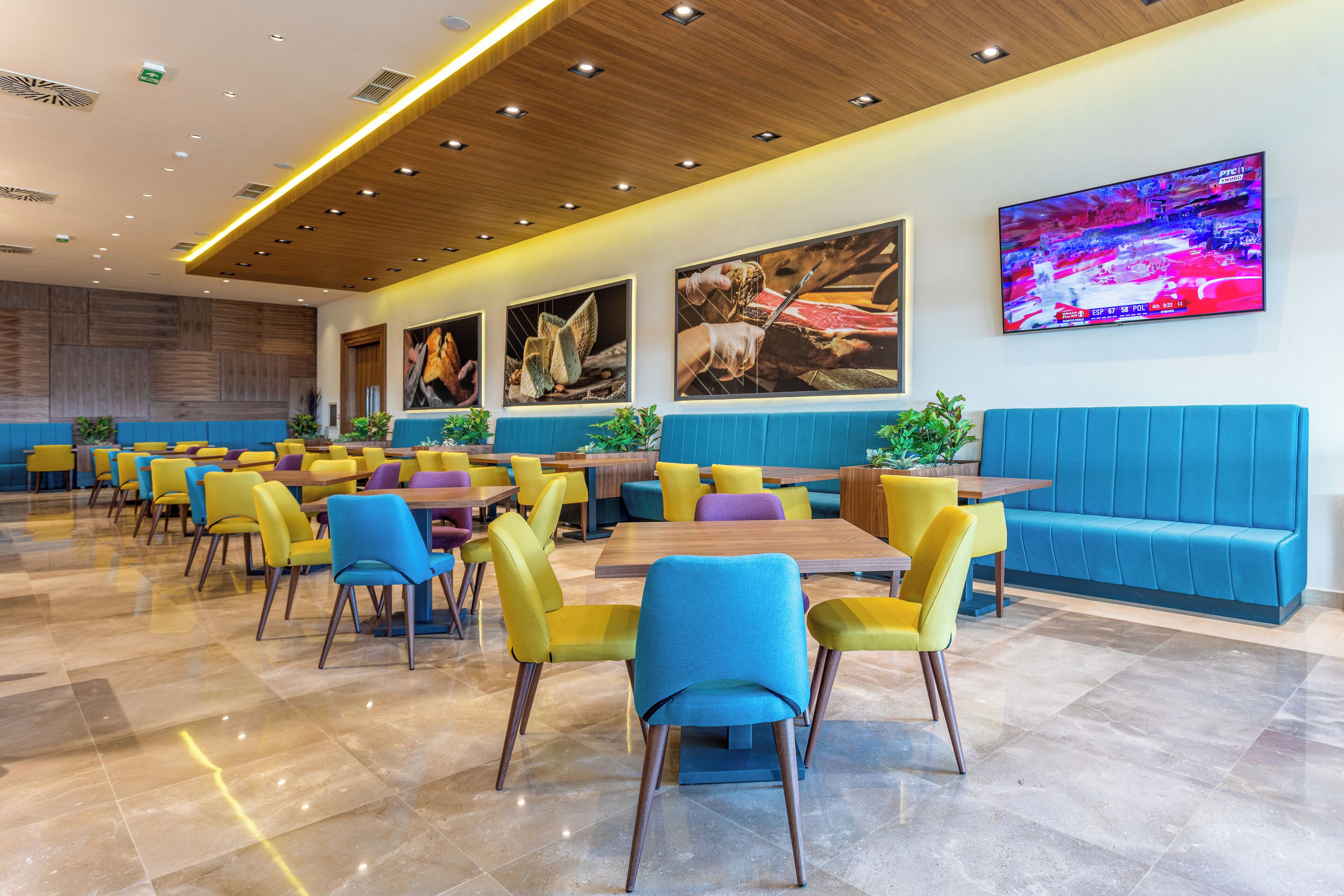 A modern dining area with multiple tables and chairs, a blue sofa, and wall art.