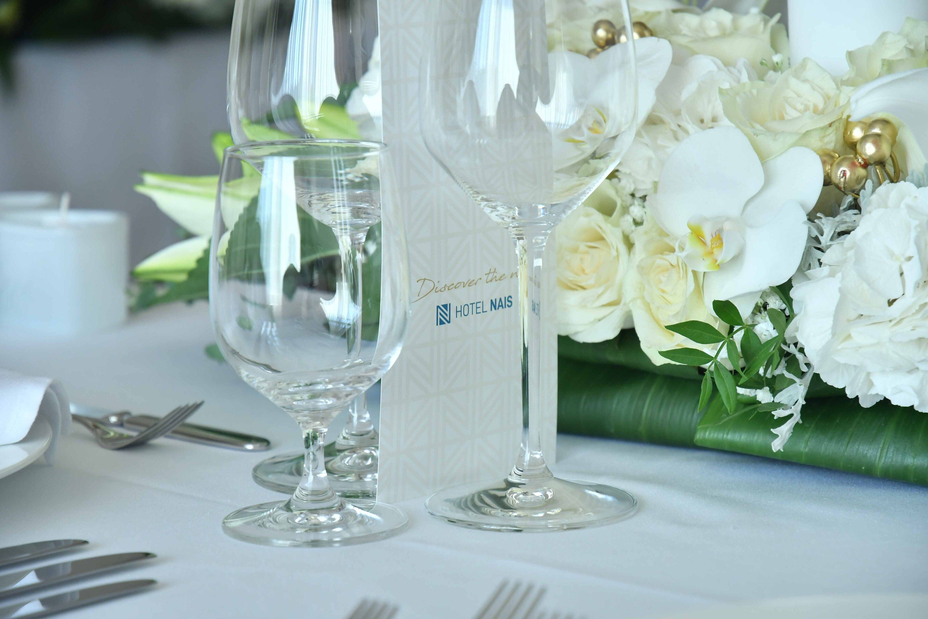 A table setting with clear glassware, a menu, and a floral arrangement.