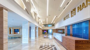 A modern hotel lobby with a reception desk, a seating area, and a large digital screen. - HOTEL NAIS (Vrtiste)