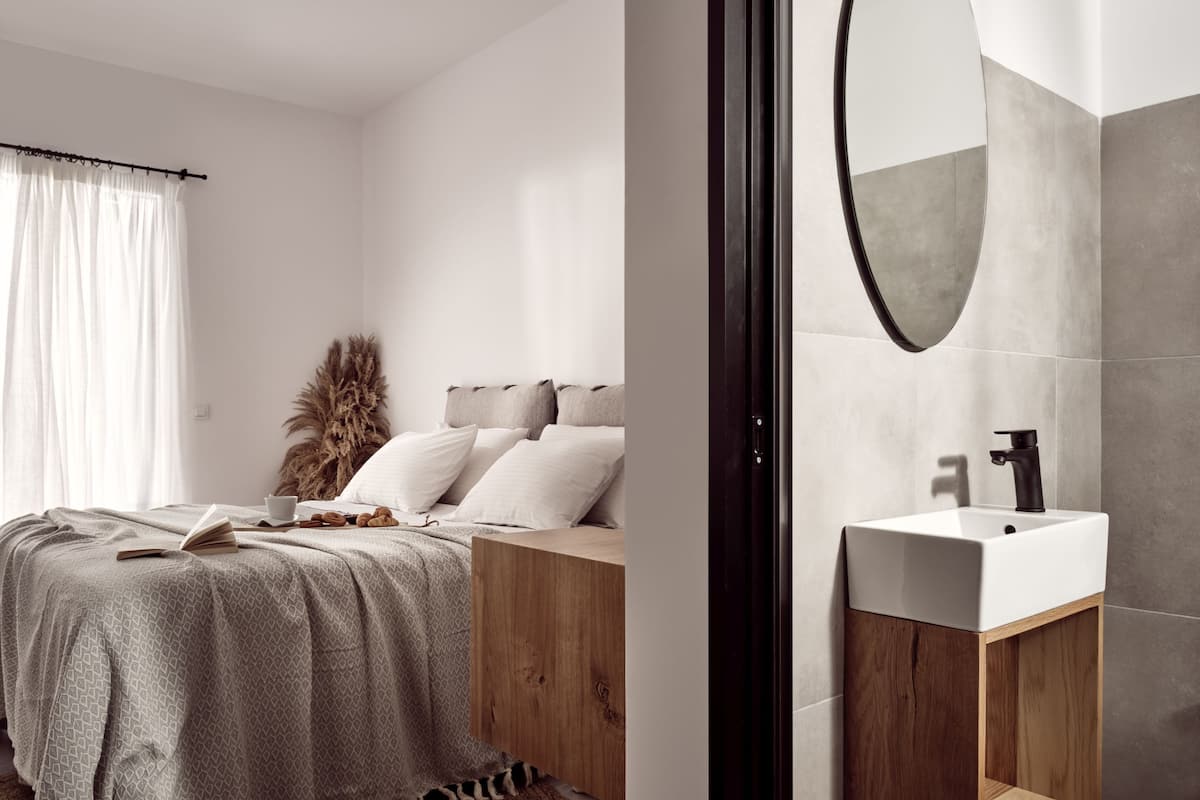 A modern bedroom with a bed, bedside table, and a large mirror.