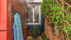 Un petit espace extérieur, à l’air libre, avec une fenêtre, une douche et une plante en pot.
