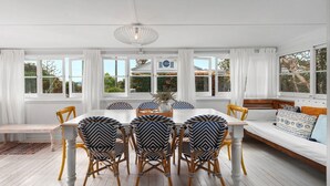 Un coin repas avec une table blanche, des chaises à motifs bleus et blancs, et un luminaire suspendu.
