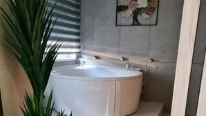 Ett modernt badrum med ett stort badkar, en krukväxt och en minimalistisk design.