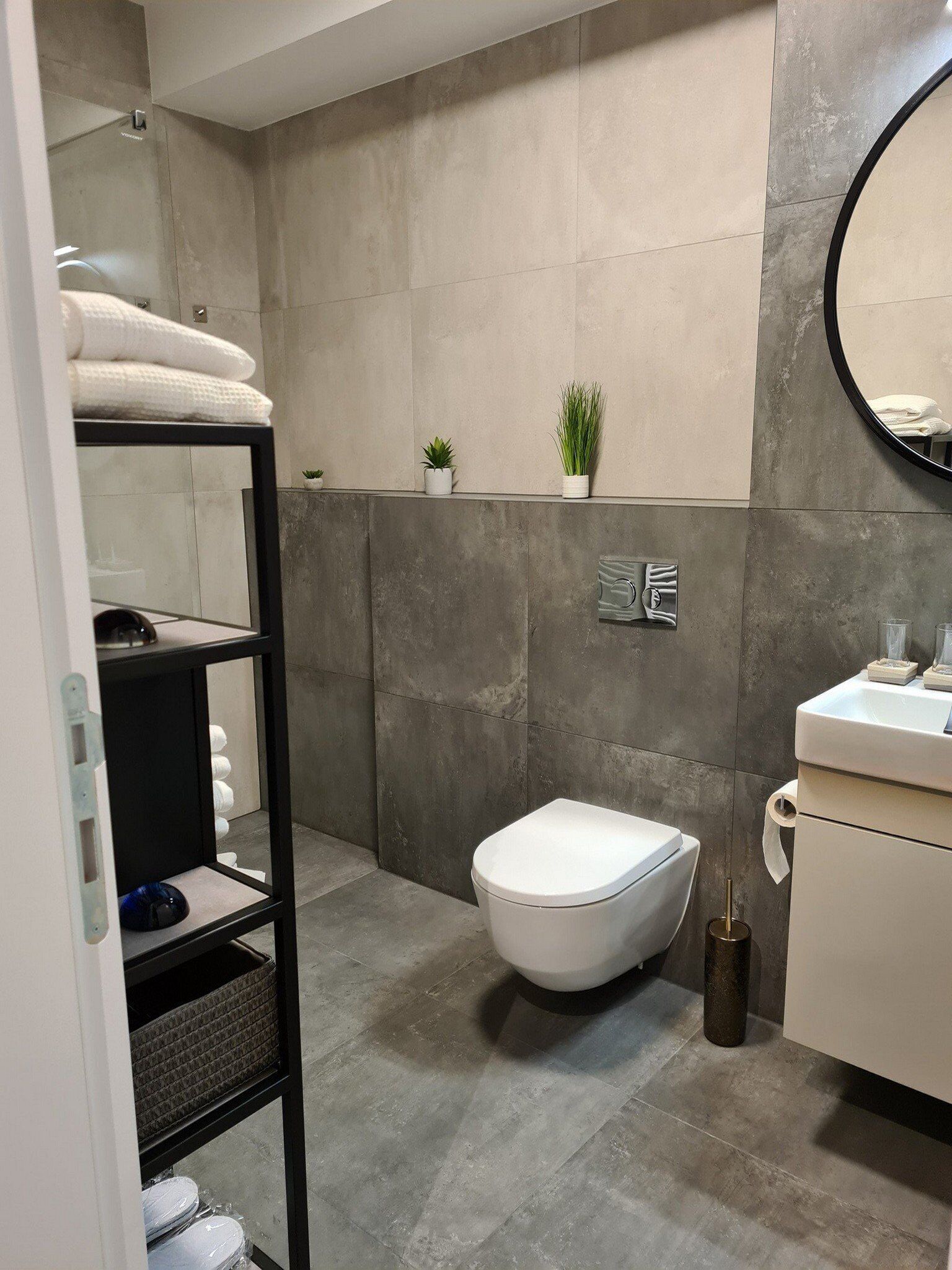 A modern bathroom with a toilet, sink, and shelves.