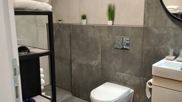 A modern bathroom with a toilet, sink, and shelves.