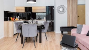 Une cuisine moderne avec un coin repas, un ordinateur portable posé sur une table d’appoint et un canapé dans le salon.
