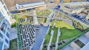 Vue aérienne d’un ensemble immobilier moderne, doté d’une cour centrale, entouré de zones de stationnement et de bâtiments adjacents.