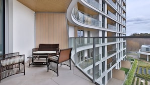 Un bâtiment moderne doté d’un balcon incurvé, d’un espace extérieur aménagé pour s’asseoir et d’un jardin.