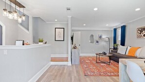 A modern living room with a sofa, coffee table, and a rug. There is a staircase leading to another level.