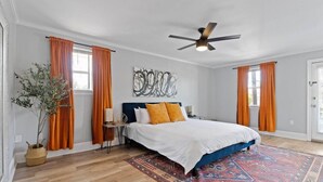 A bedroom with a bed, a ceiling fan, a potted plant, and a rug.