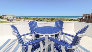 A terrace with a round table and four blue chairs, overlooking a beach and ocean. - Creston House 3C~Sunrise to Sunset, the Upper Deck is the Place to be (St. Augustine)