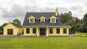 A yellow house with a dark roof, a front porch, and a chimney. - Large Country House, Sleeps 10, Family Friendly (Westport)