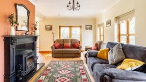 A living room with a fireplace, a sofa, and a patterned rug. - Large Country House, Sleeps 10, Family Friendly (Westport)