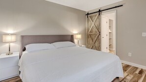 Un dormitori amb un llit gran, dues làmpades de nit, un armari de fusta i un ventilador de sostre.