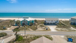 Ein Küstenanwesen mit Blick auf den Strand, inklusive eines Hauses mit Garage und einem separaten Gebäude mit großem Fenster.