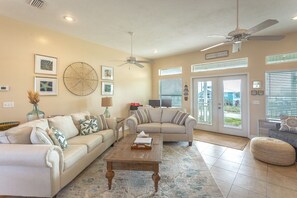 A spacious living room with a beige sofa, a wooden coffee table, and a ceiling fan.