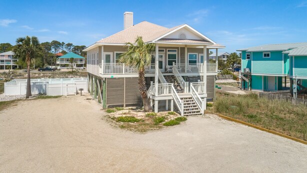 Ein Strandhaus mit Balkon, Treppe und Blick aufs Meer.