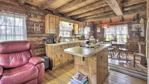 A rustic cabin interior with a leather recliner, wooden kitchen, and a dining area. - Quaint & Quiet Belleview Cabin on 35 Acres! (Belleview)