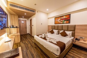 Een moderne hotelkamer met een groot bed, een houten hoofdbord, een nachtkastje met een telefoon en een schilderij aan de muur.