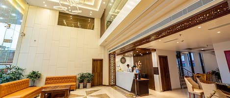 A modern hotel lobby with a reception desk, seating area, and a geometric patterned floor.