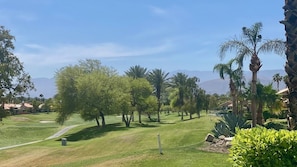 Ein Golfplatz mit gepflegtem Rasen, Bäumen und blauem Himmel.