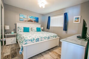 A bedroom with a bed, bedside tables, a desk, and a window with curtains.
