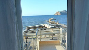 A view from a window overlooking a pier with metal railings and a small structure, leading to a rocky island in the distance. - Litinas Casa-In front of the Sea (Chania)