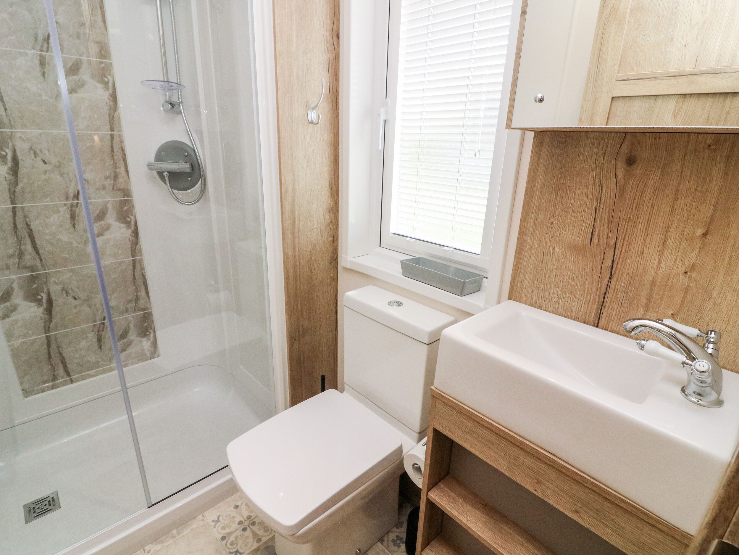 A bathroom with a shower, toilet, sink, and window.