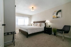 Relax in this serene bedroom with a large bed, bedside tables, and a comfortable chair.