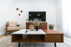 Relax in this stylish living room with a large flat-screen TV, comfortable armchair, and coffee table.