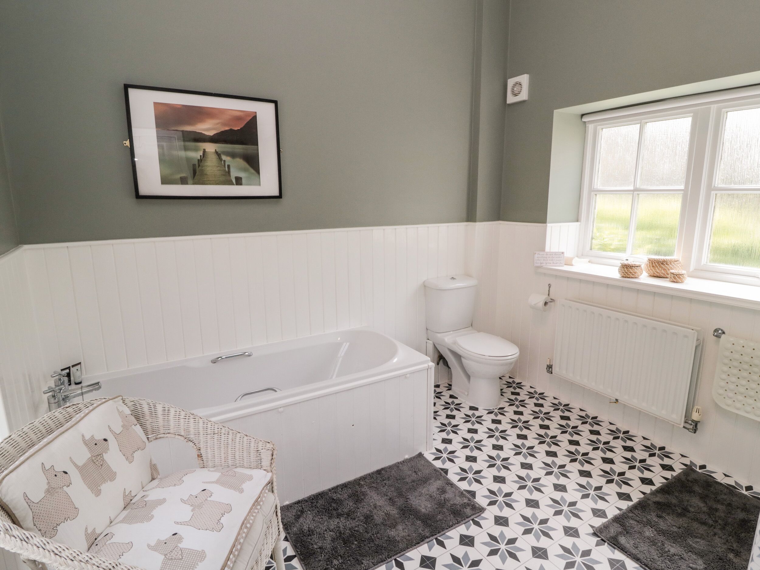 A bathroom with a bathtub, toilet, and a window with a view.