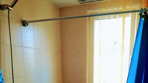 A small bathroom with a toilet, a shower, and a window. - Lovely apartment for rent in a quiet Sofia suburb. (Sofia)