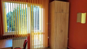A room with a large window, a wooden wardrobe, a red chair, and a patterned rug. - Lovely apartment for rent in a quiet Sofia suburb. (Sofia)