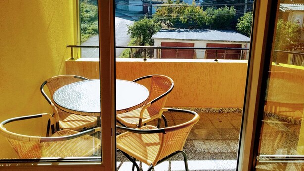 A balcony with wicker chairs and a small table, overlooking a residential area with colorful buildings. - Lovely apartment for rent in a quiet Sofia suburb. (Sofia)