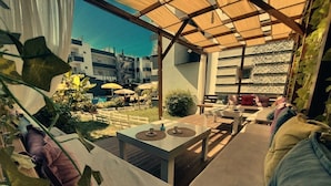 A patio area with outdoor seating, a table, and a view of the cityscape. - Summer Rose Hotel (Manavgat)