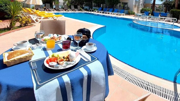 A poolside breakfast setup with a table, chairs, and a buffet. - Summer Rose Hotel (Manavgat)