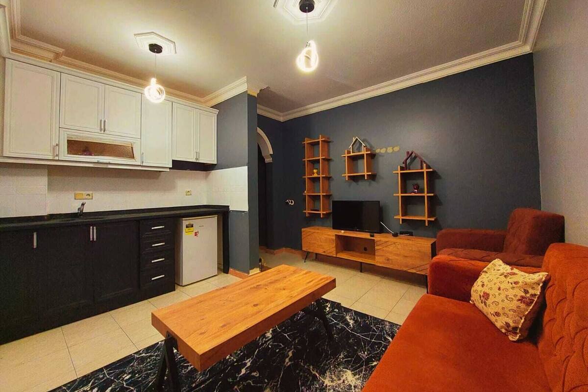 A modern living room with a wooden coffee table, orange sofa, and a TV stand.