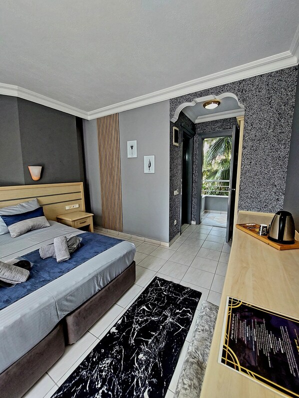 Une chambre moderne avec un lit, des tables de chevet, une petite table, un tapis à motifs noir et blanc et un bureau en bois avec une bouilloire.
