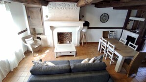 Una sala de estar acogedora con chimenea, un sofá y un comedor con mesa y sillas.