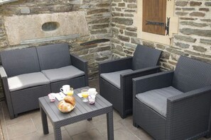 Relax in this inviting outdoor seating area with a stone wall backdrop, featuring two sofas and a small table.