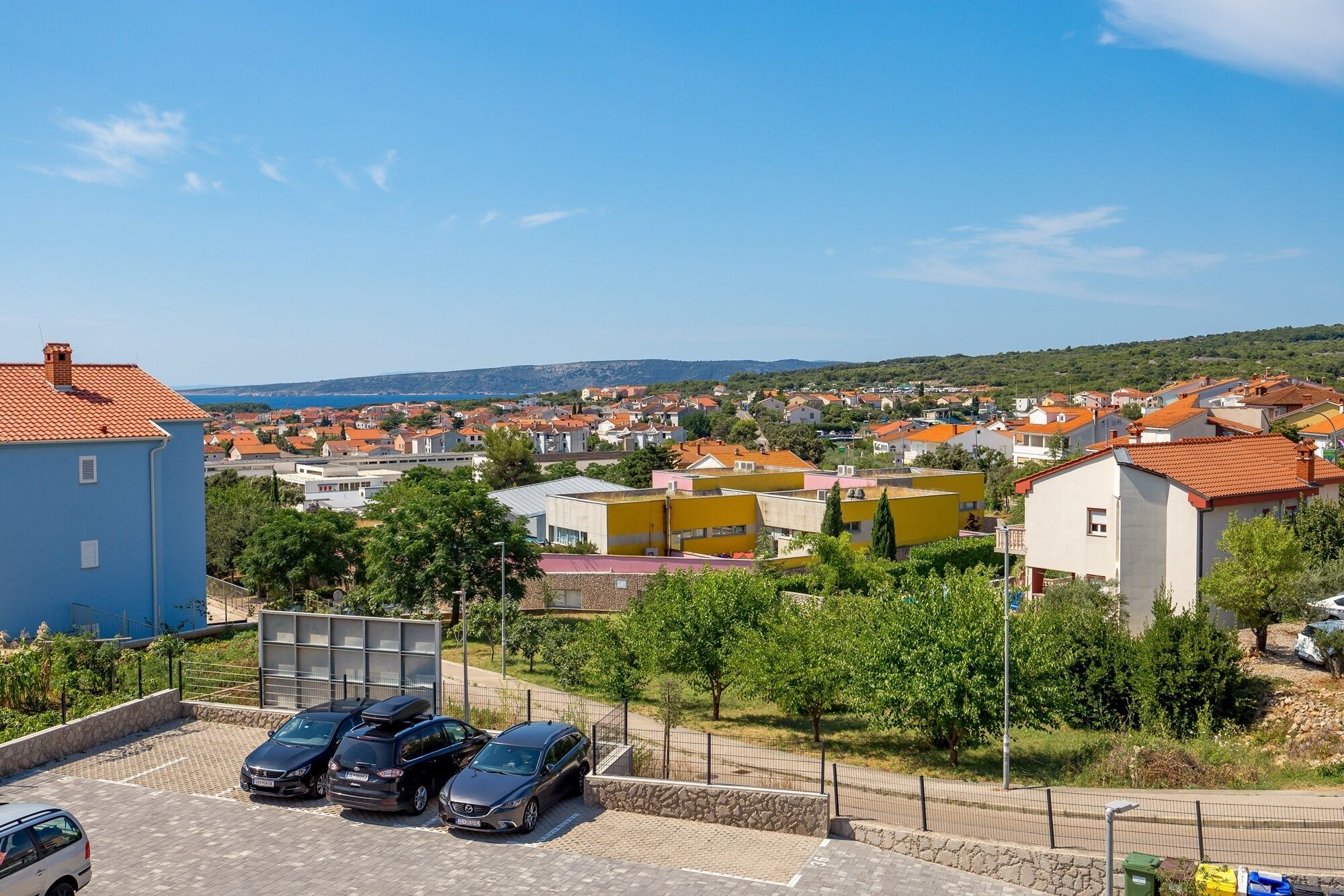 Asuinalue, jossa on taloja, parkkipaikka ja esteetön näkymä merelle.