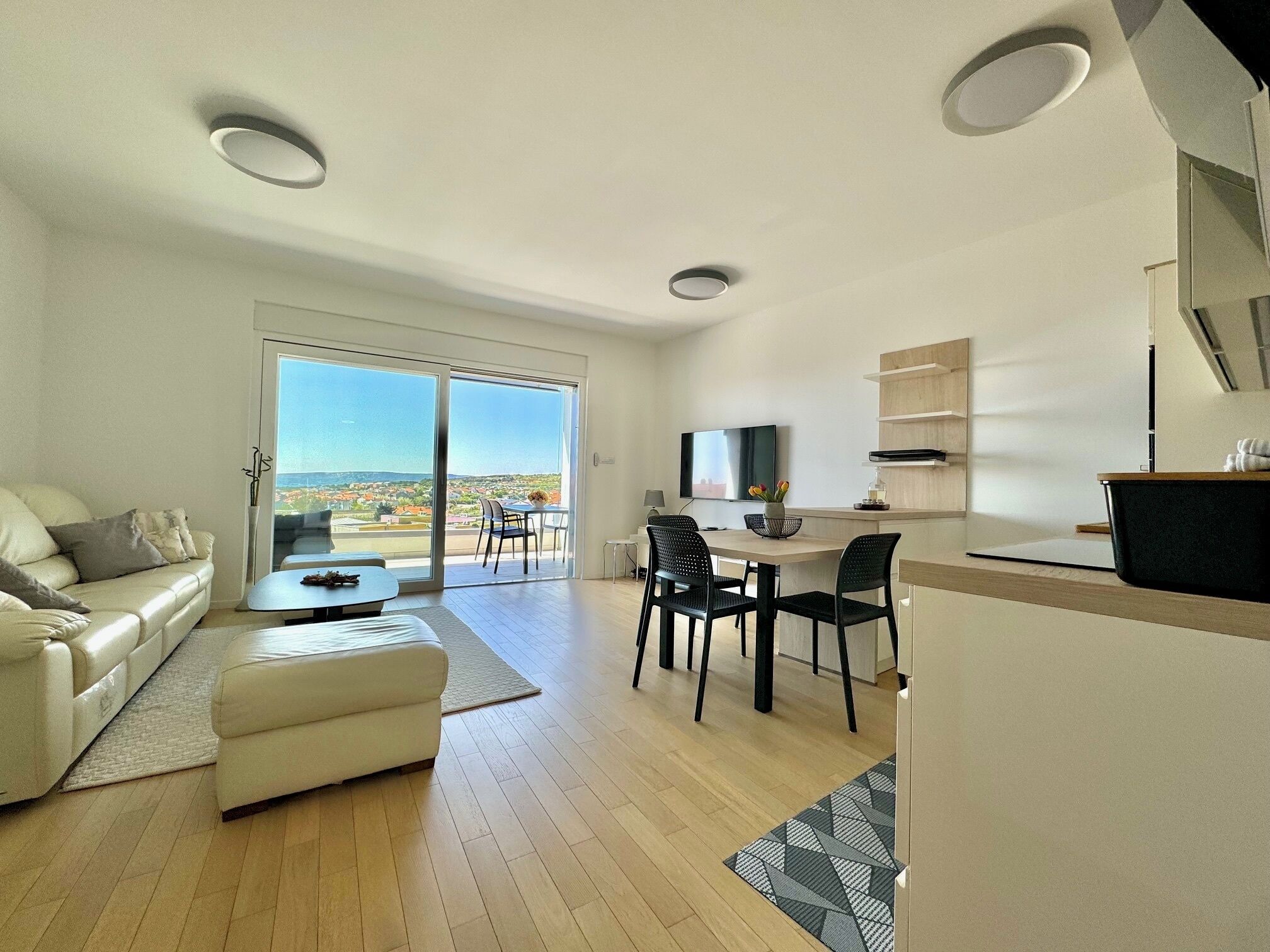 Uma sala de estar moderna com sofá, mesa de centro e área de jantar com cadeiras e televisão.