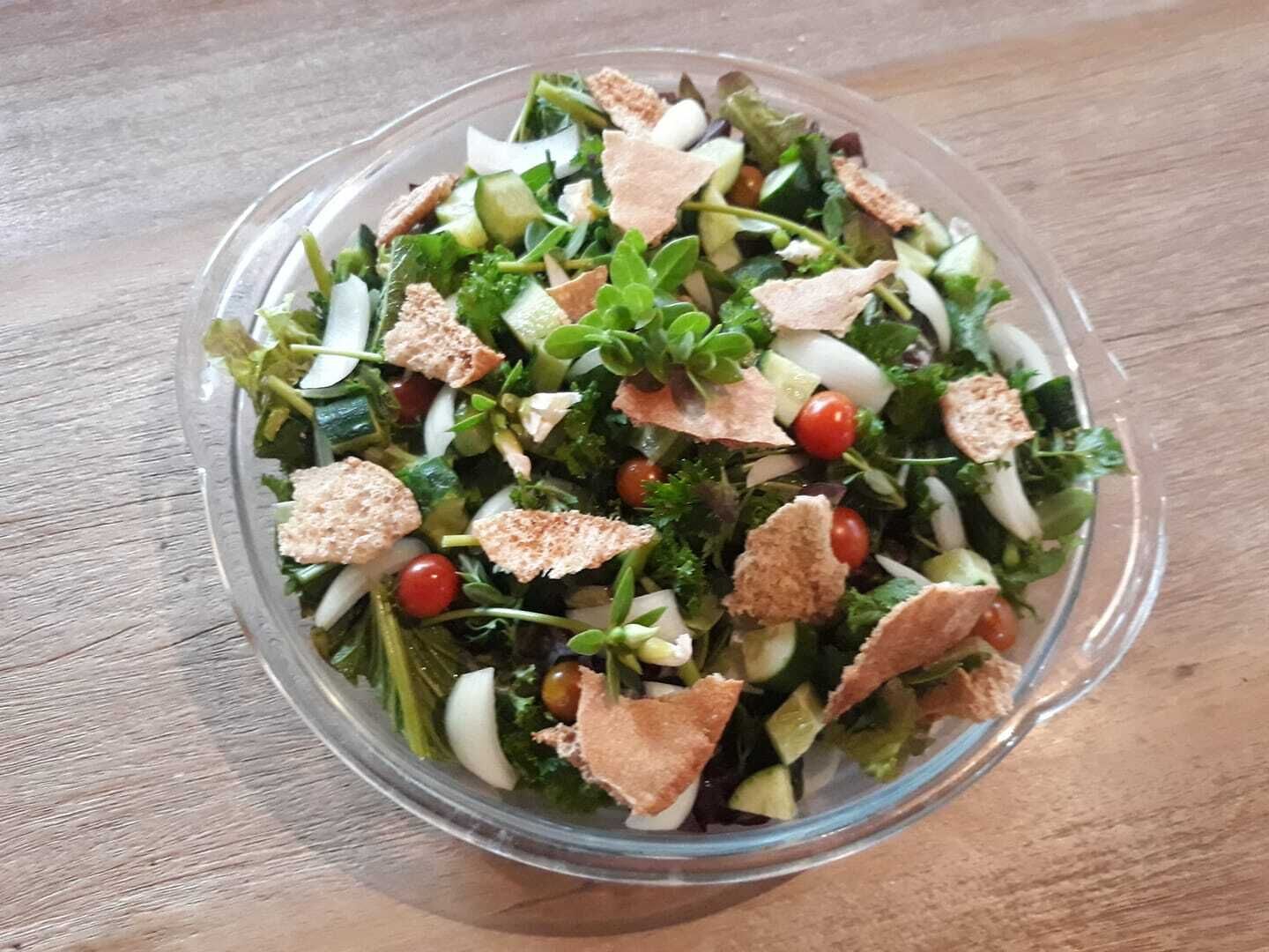 Se ve claramente un bol de ensalada sobre una mesa de madera.