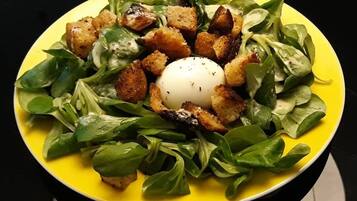 A plate of food with a poached egg, croutons, and greens.