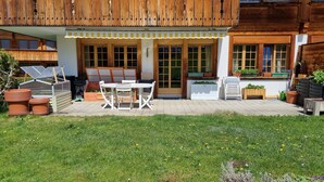 A wooden house with a patio, a table and chairs, and potted plants. - Room with extra-large double-bed, cable TV, private bathroom, organic breakfast, (Lauenen)