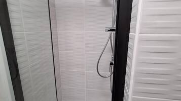 Eine moderne Dusche mit Handbrause und am Wand montiertem Wasserhahn.
