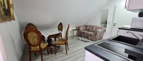 A compact living space with a dining area, sofa, and kitchenette.