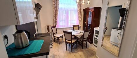 Una cocina compacta con comedor, un espejo grande y un mueble con puerta de vidrio.